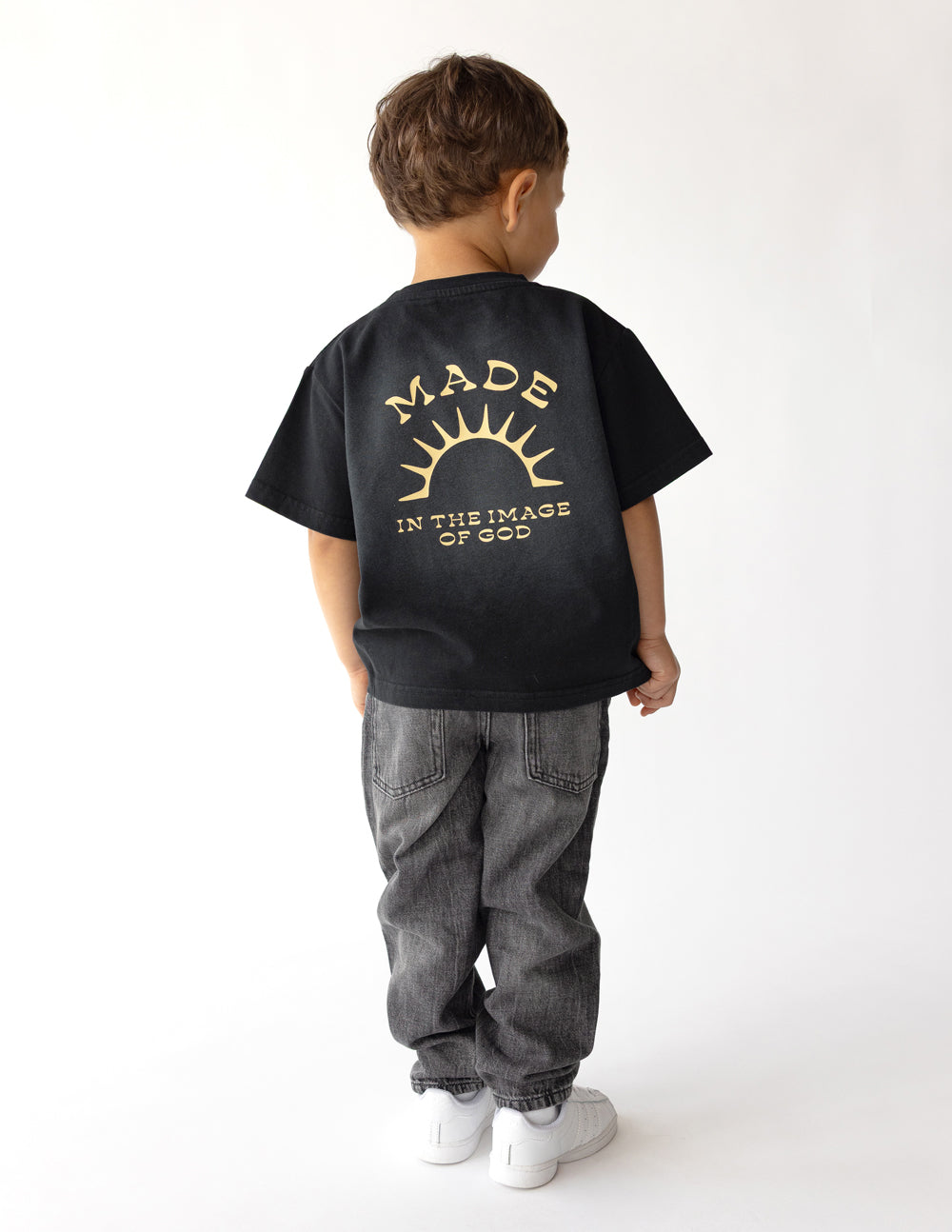 Kids black graphic tee with gold sunburst logo on the back