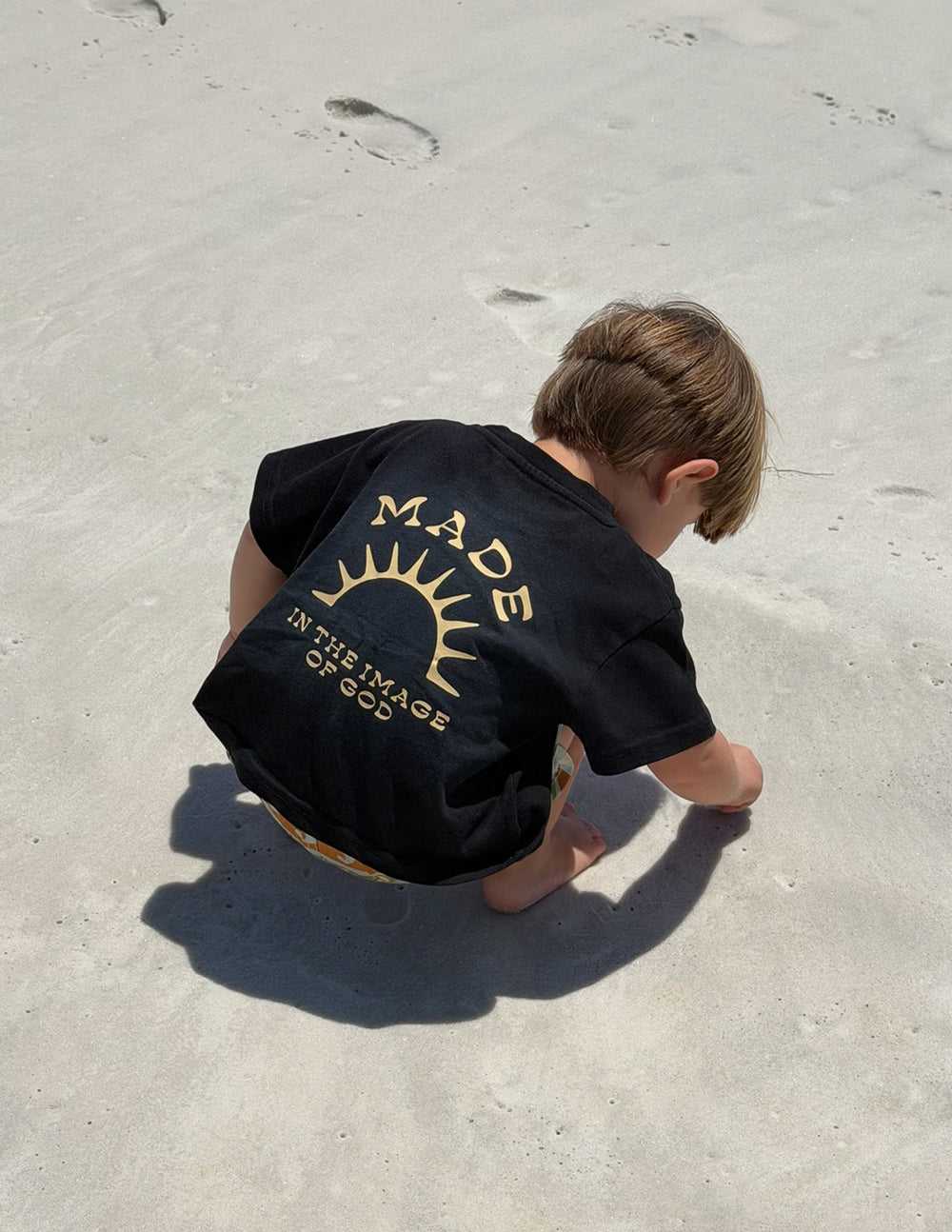 Kids black graphic tee with gold back print sunburst and text