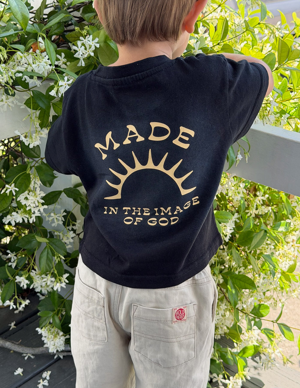 Kids black graphic tee back close-up with gold sunburst 'MADE' print