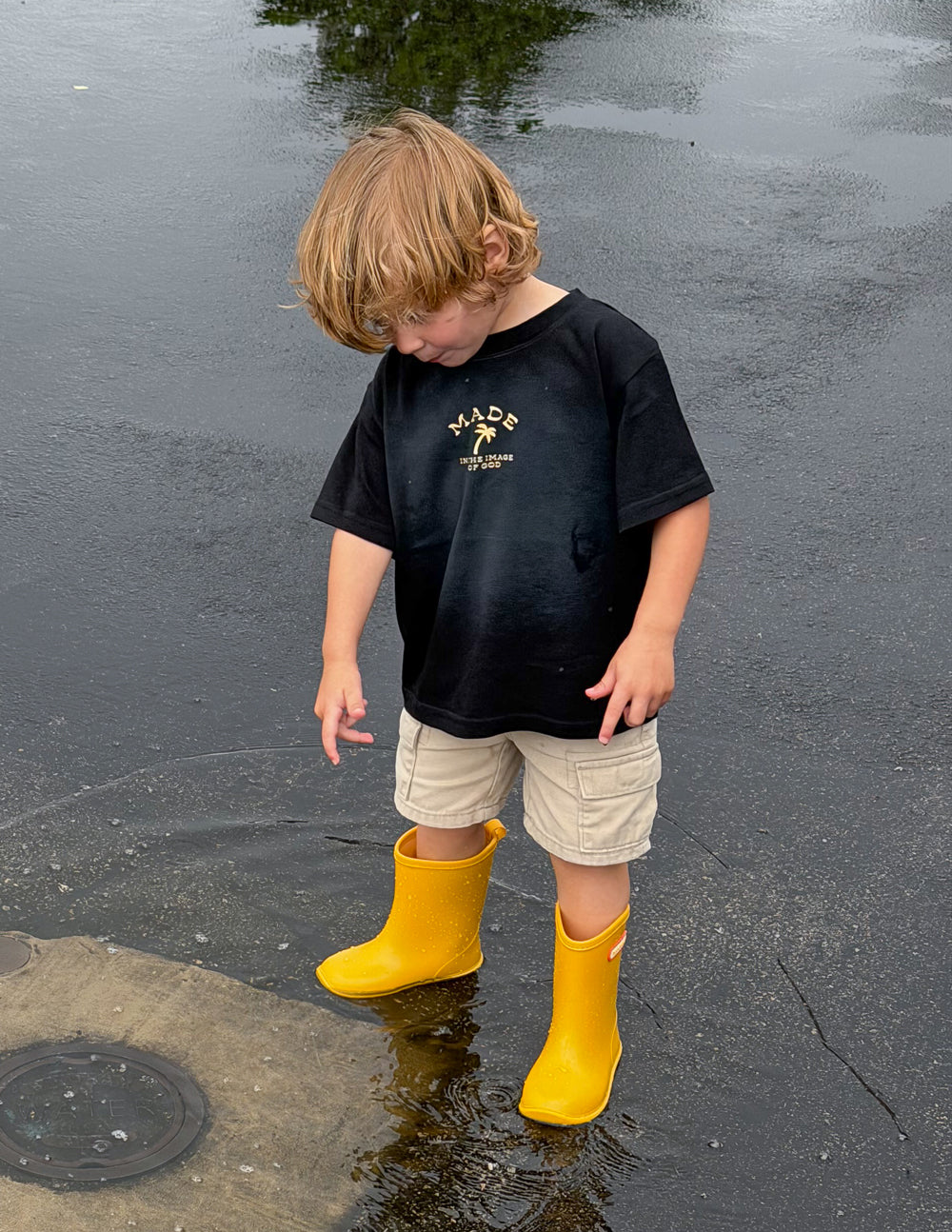 Kids black graphic tee with small gold front logo and scripture text