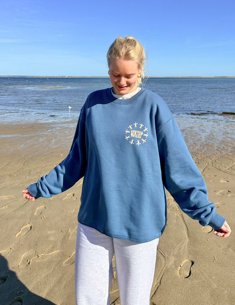 Blue unisex crewneck sweatshirt with small worship graphic at chest