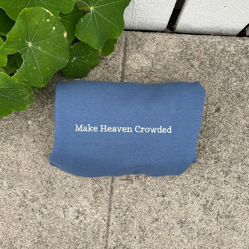 Blue crewneck sweatshirt with embroidered text: Make Heaven Crowded