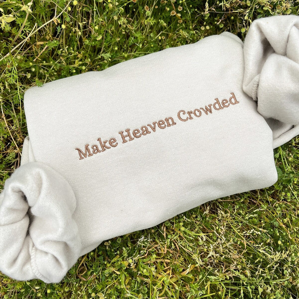 White sweatshirt back embroidered with text: Make Heaven Crowded