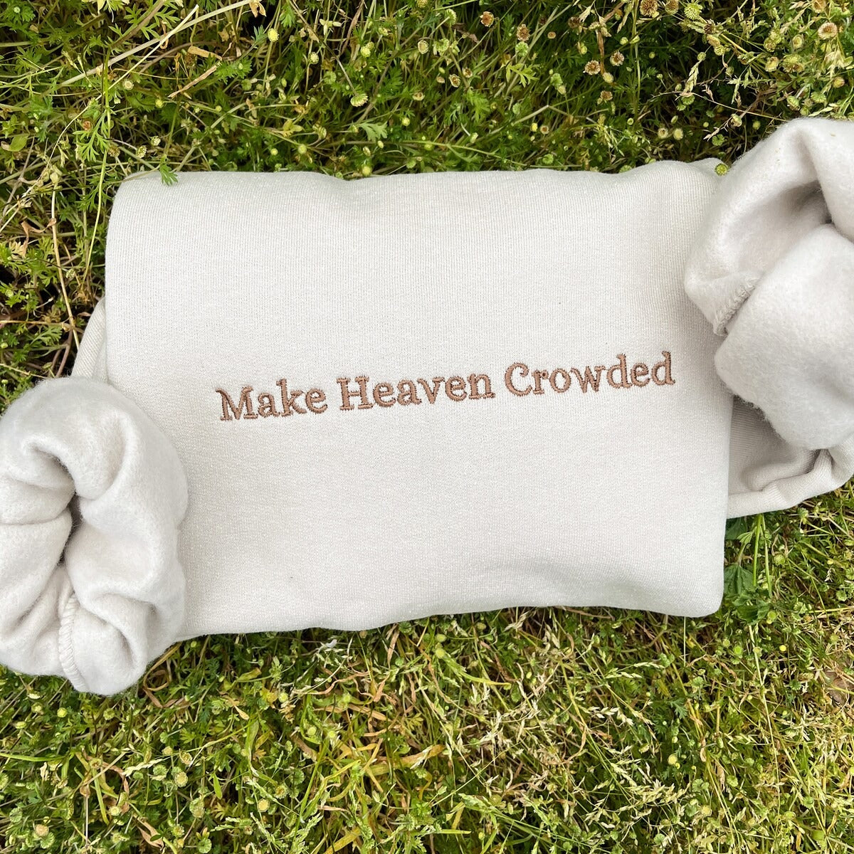 White crewneck sweatshirt with embroidered text: Make Heaven Crowded