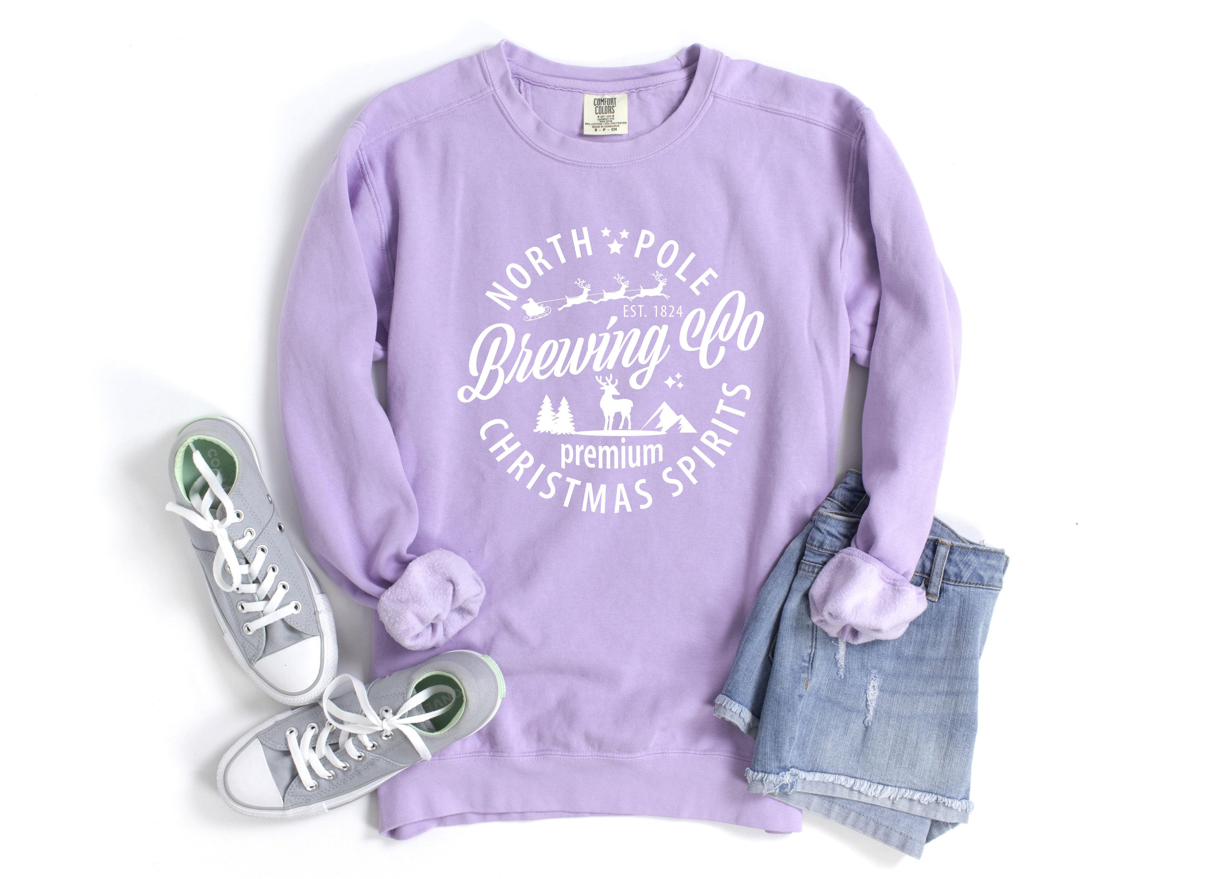 Lavender crewneck sweatshirt with holiday logo graphic; ribbed cuffs and hem