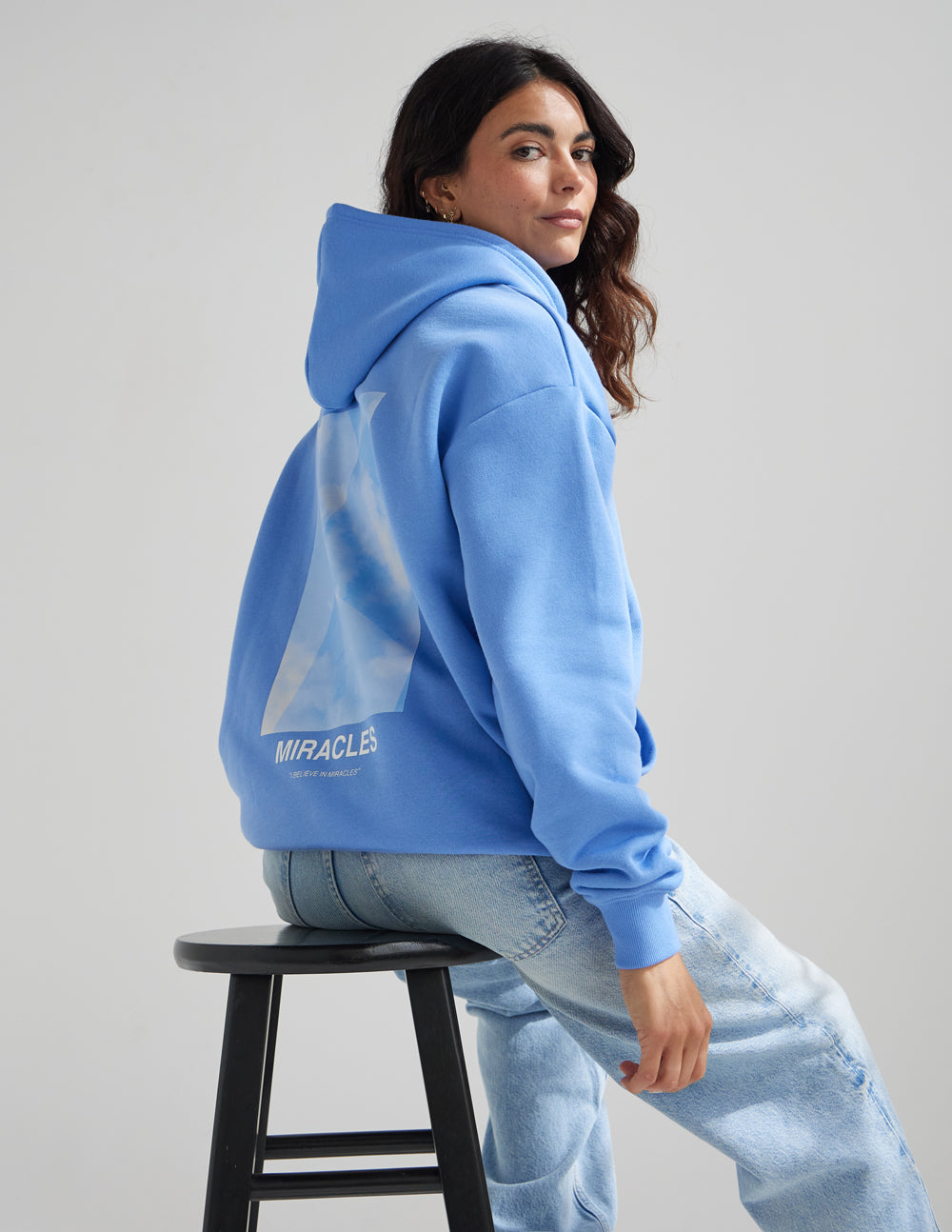 Unisex blue hoodie back view with hood and MIRACLES graphic