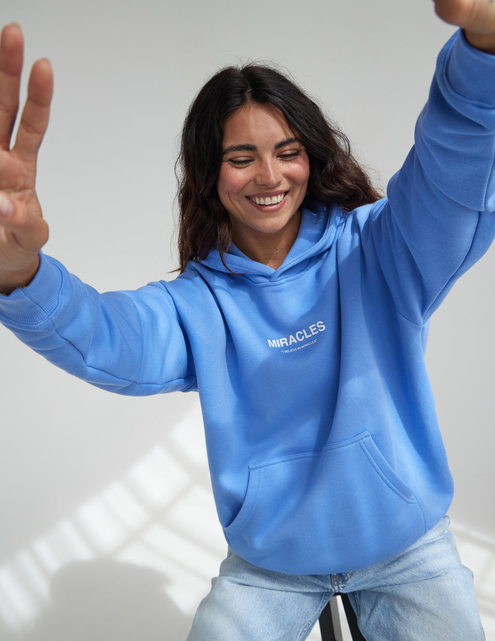 Unisex blue hoodie with hood, front pocket, and MIRACLES chest logo
