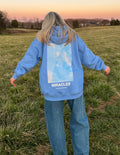 Blue unisex hoodie with hood, back graphic window, and MIRACLES text