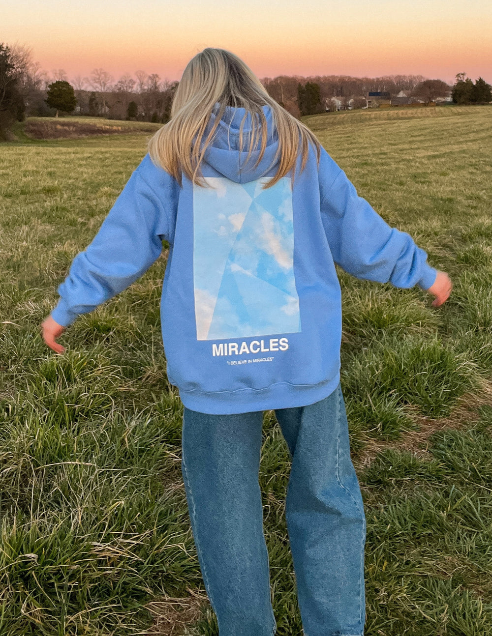 Blue unisex hoodie with hood, back graphic window, and MIRACLES text