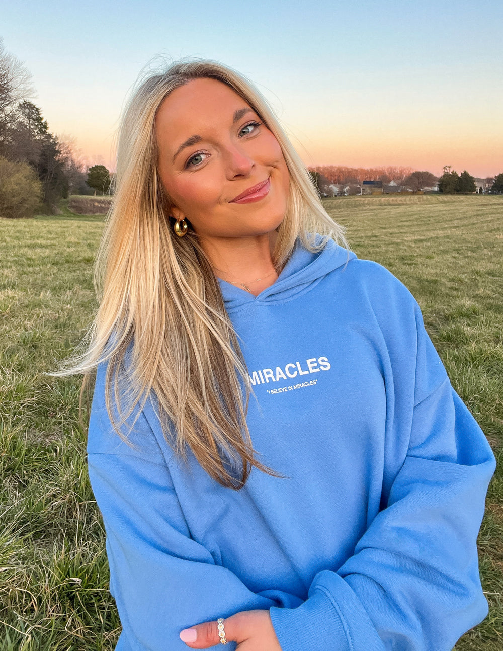 Blue unisex hoodie with hood and MIRACLES chest logo, front pocket