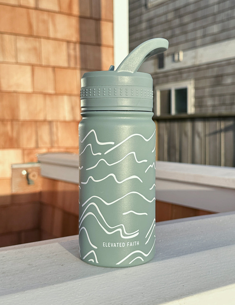 Sage green kids water bottle with white mountainscape wave graphic and flip straw cap