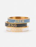 Enamel ring set of two stacked bands: blue JIREH, black JESUS, gold-tone edges.