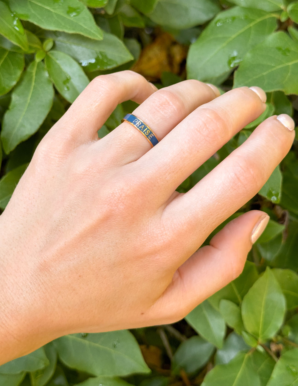 Navy enamel praise band ring on finger with gold edges and “PRAISE” text