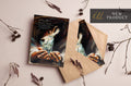 Greeting cards with dark angel artwork, in brown kraft sleeves, on twig decoration.