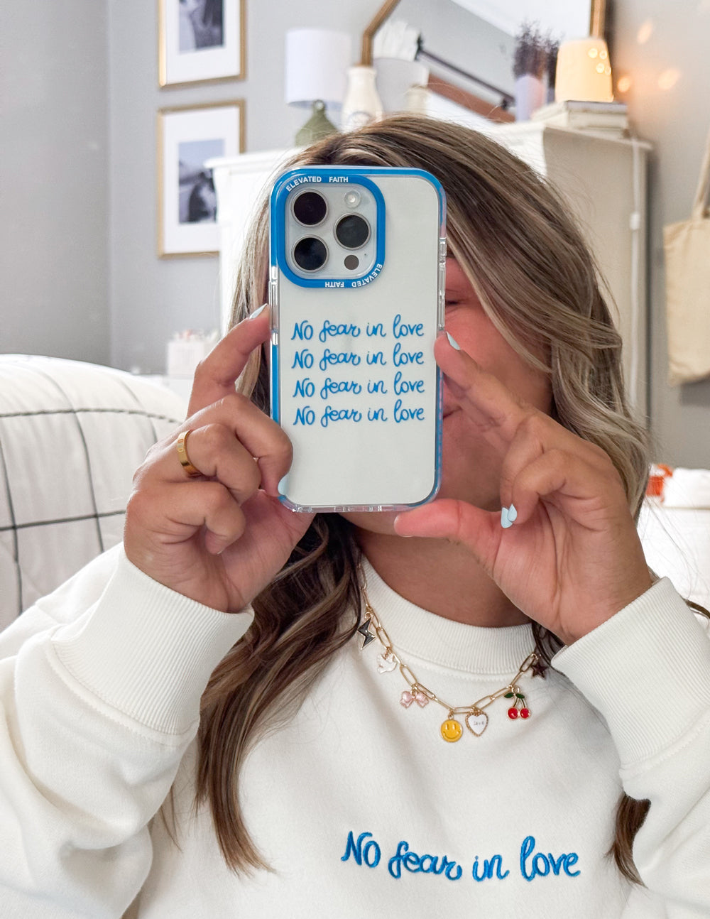Blue transparent phone case held up by hand; 'No fear in love' printed on back