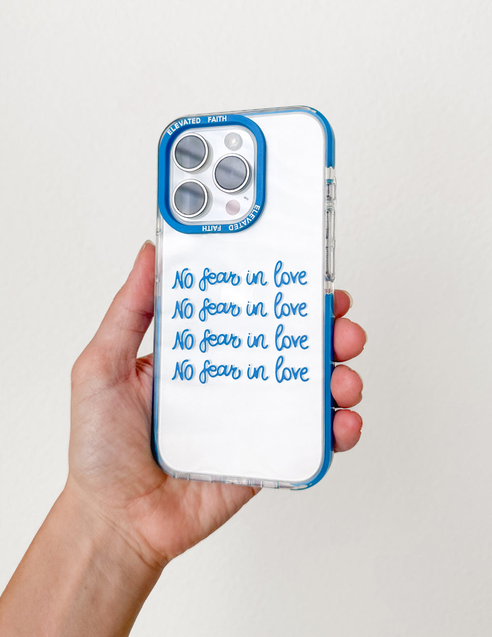 Blue transparent phone case held in hand; 'No fear in love' text on back