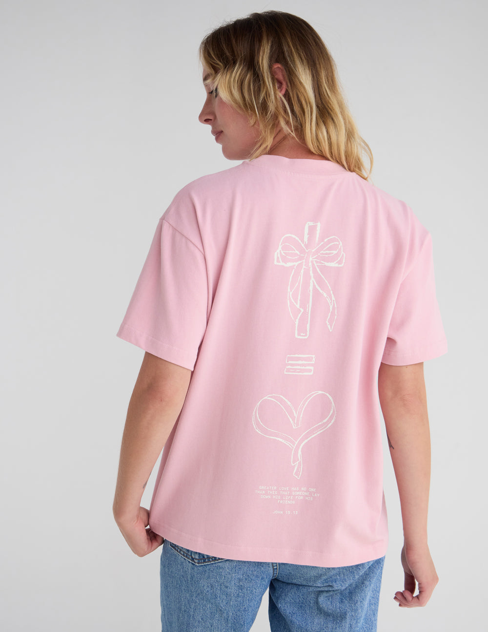 Unisex pink T-shirt back view with bow and heart line-art graphic, crew neck.