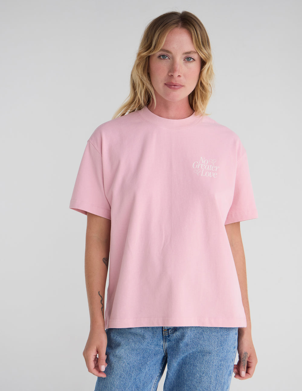 Unisex pink T-shirt with small bow and text graphic at left chest.