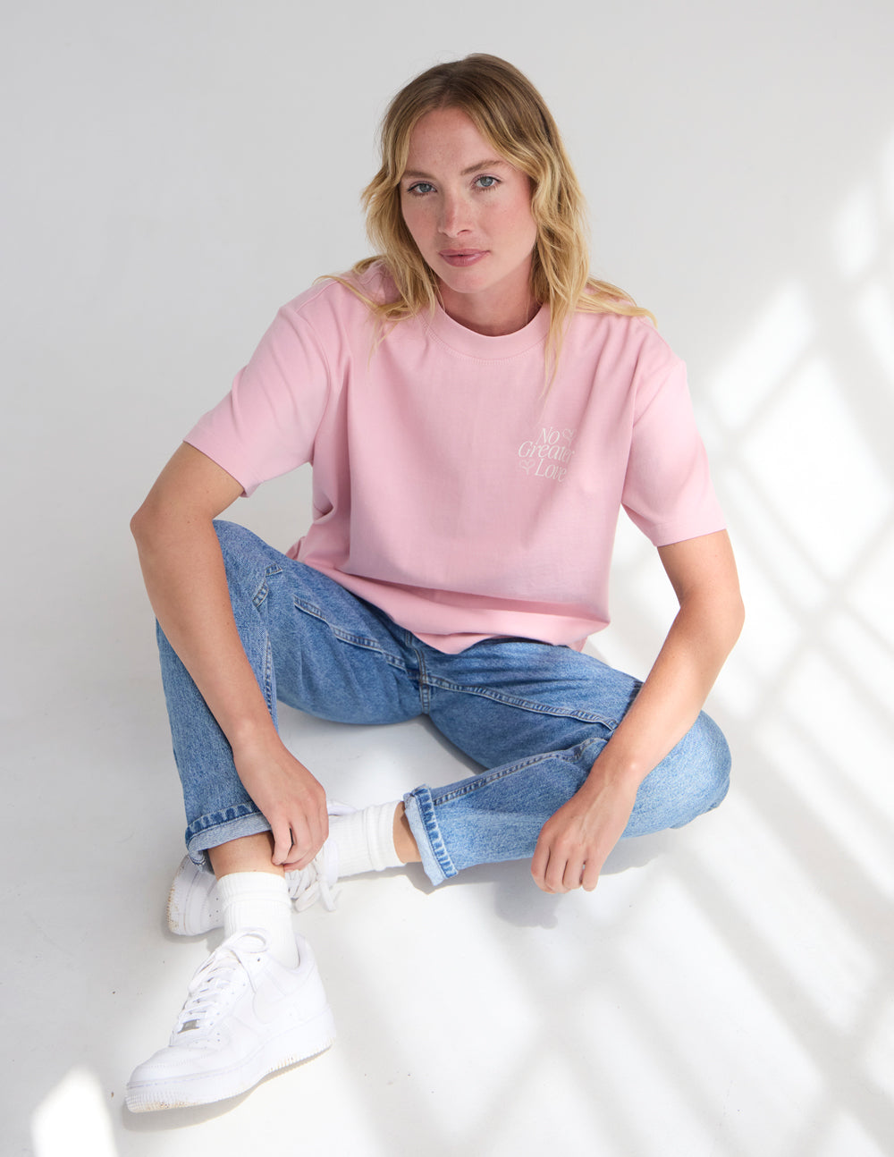 Unisex pink T-shirt with small bow and text graphic at left chest.
