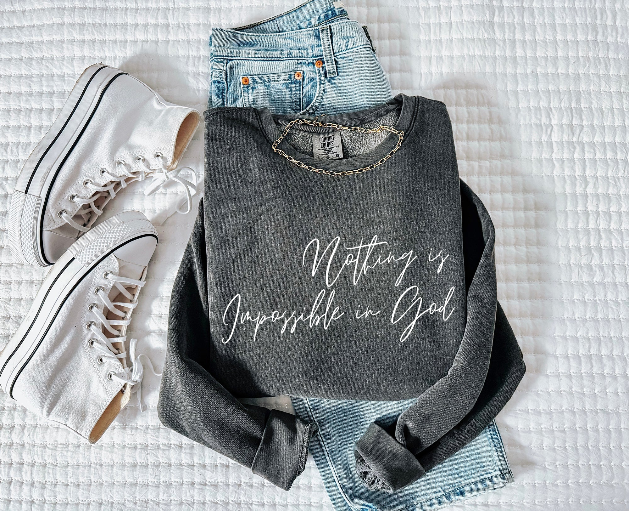 Dark crewneck sweatshirt with long sleeves and white scripture slogan print, flat lay