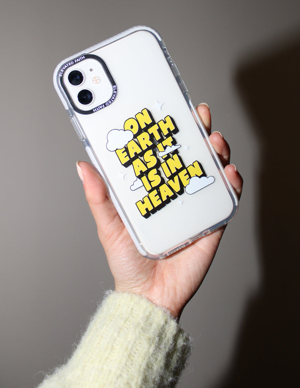 Clear phone case with multicolor text graphic and cloud icons, held in hand