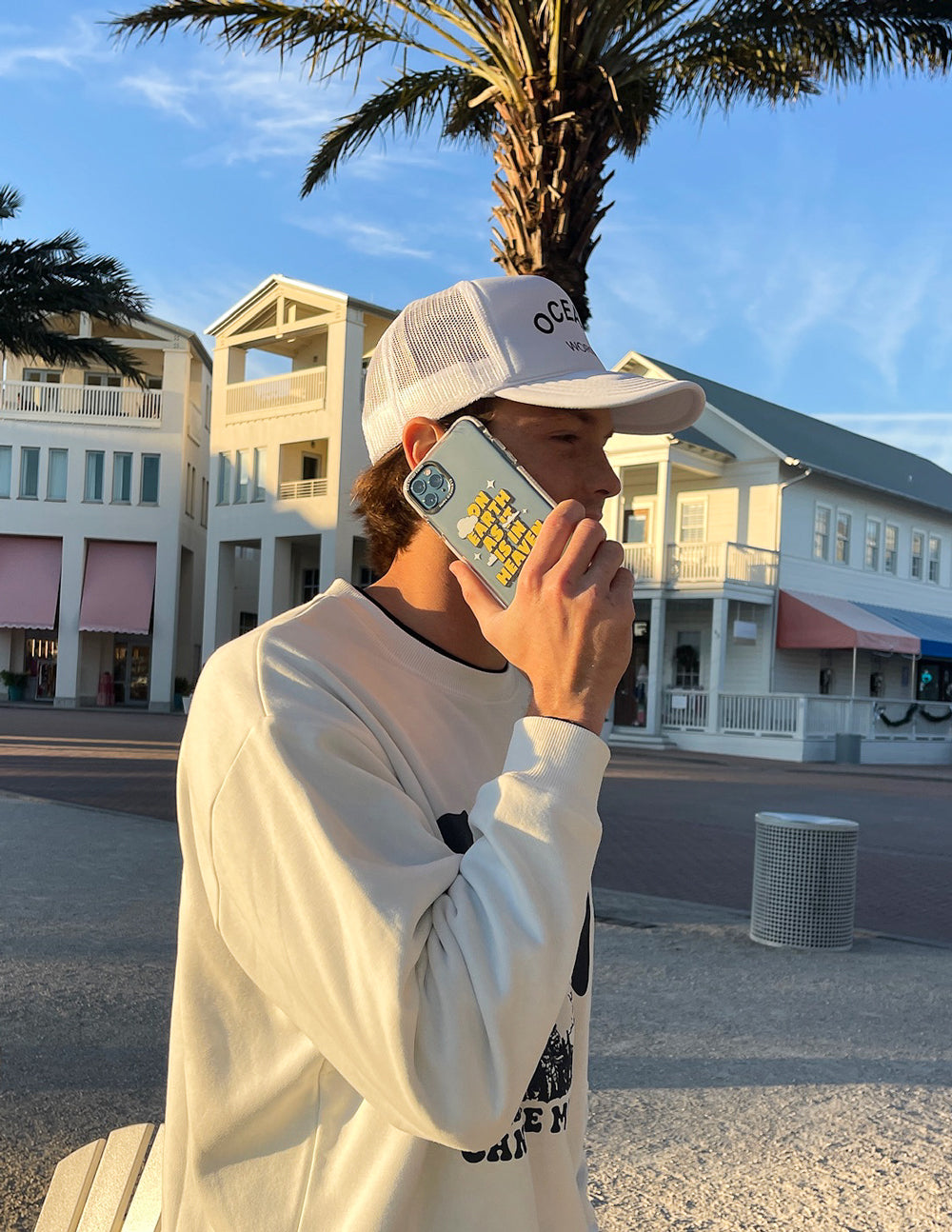 Clear phone case with yellow text and cloud icons, held up by a person