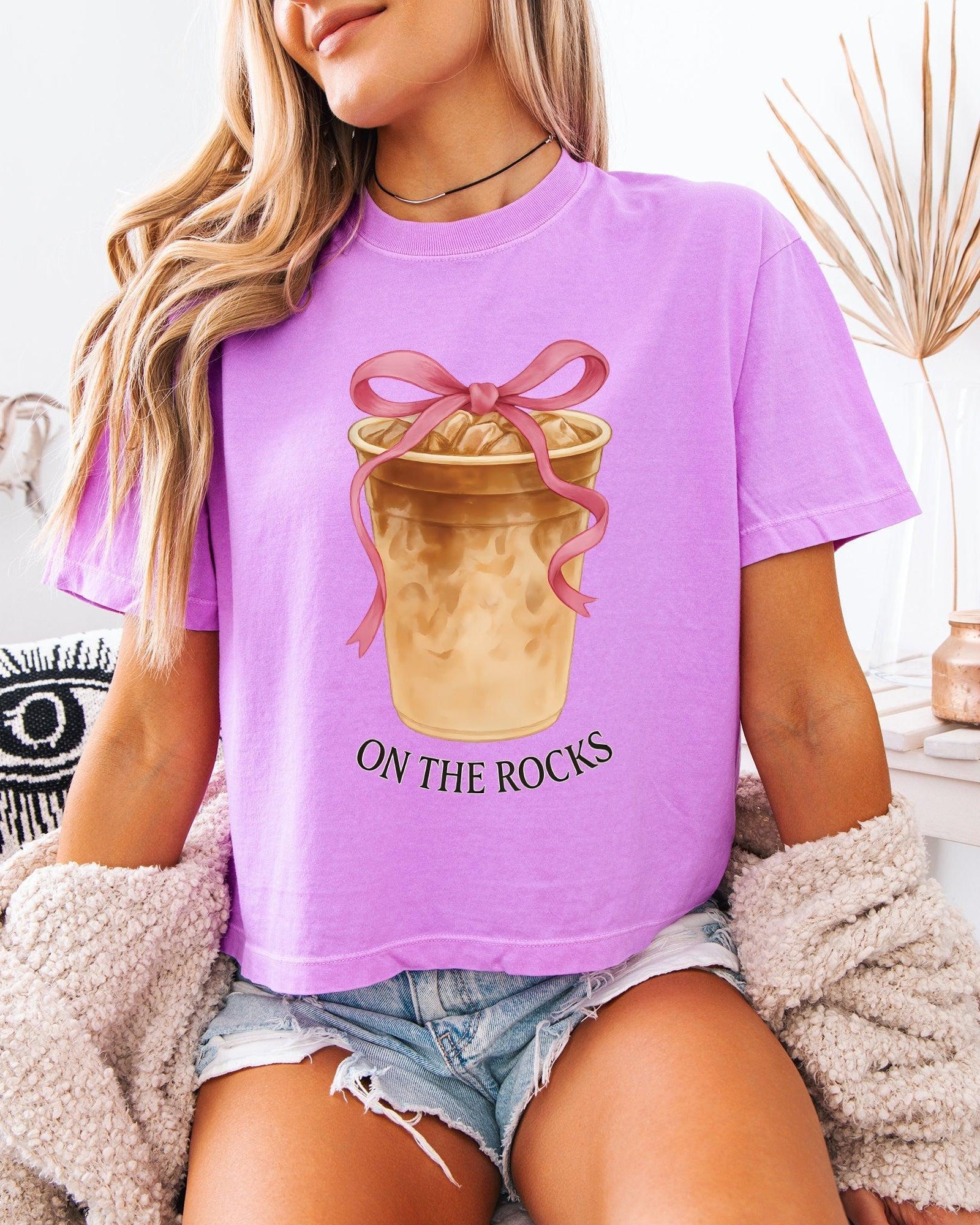 Women’s cropped T-shirt, orchid purple with pink bow latte graphic and 'ON THE ROCKS'.