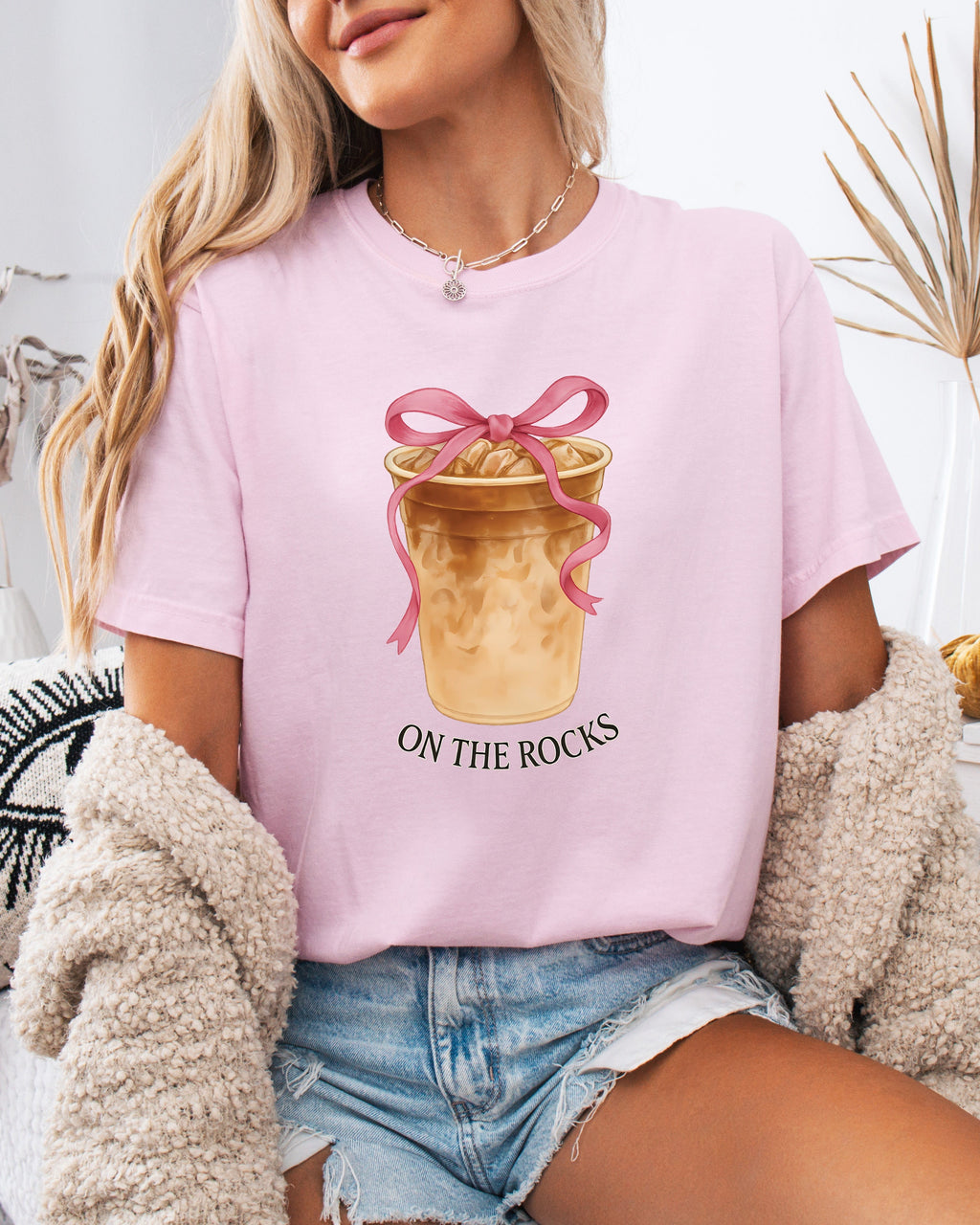 Orchid pink iced latte graphic T-shirt with “ON THE ROCKS” text under bow