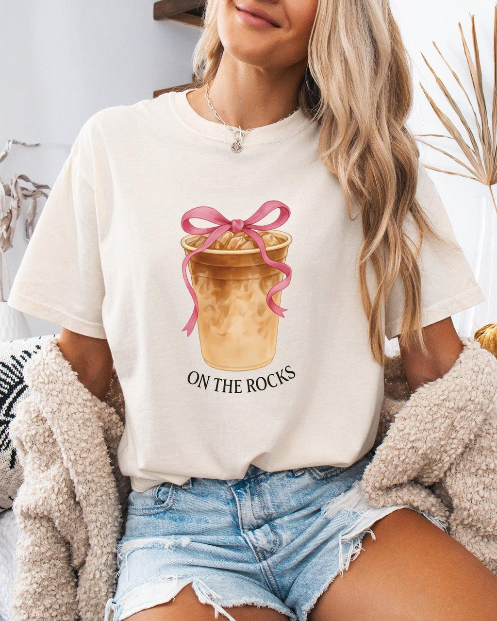 Ivory T-shirt with iced latte cup graphic, pink ribbon bow, and "On the Rocks" print