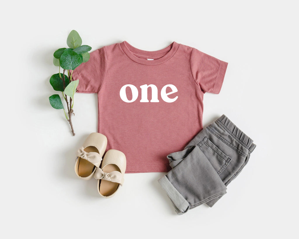 Pink baby T-shirt with “one” serif print, short sleeves