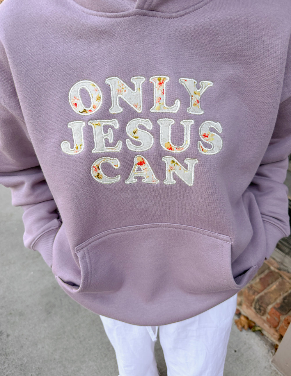 Lilac unisex hoodie close-up of "ONLY JESUS CAN" chest graphic