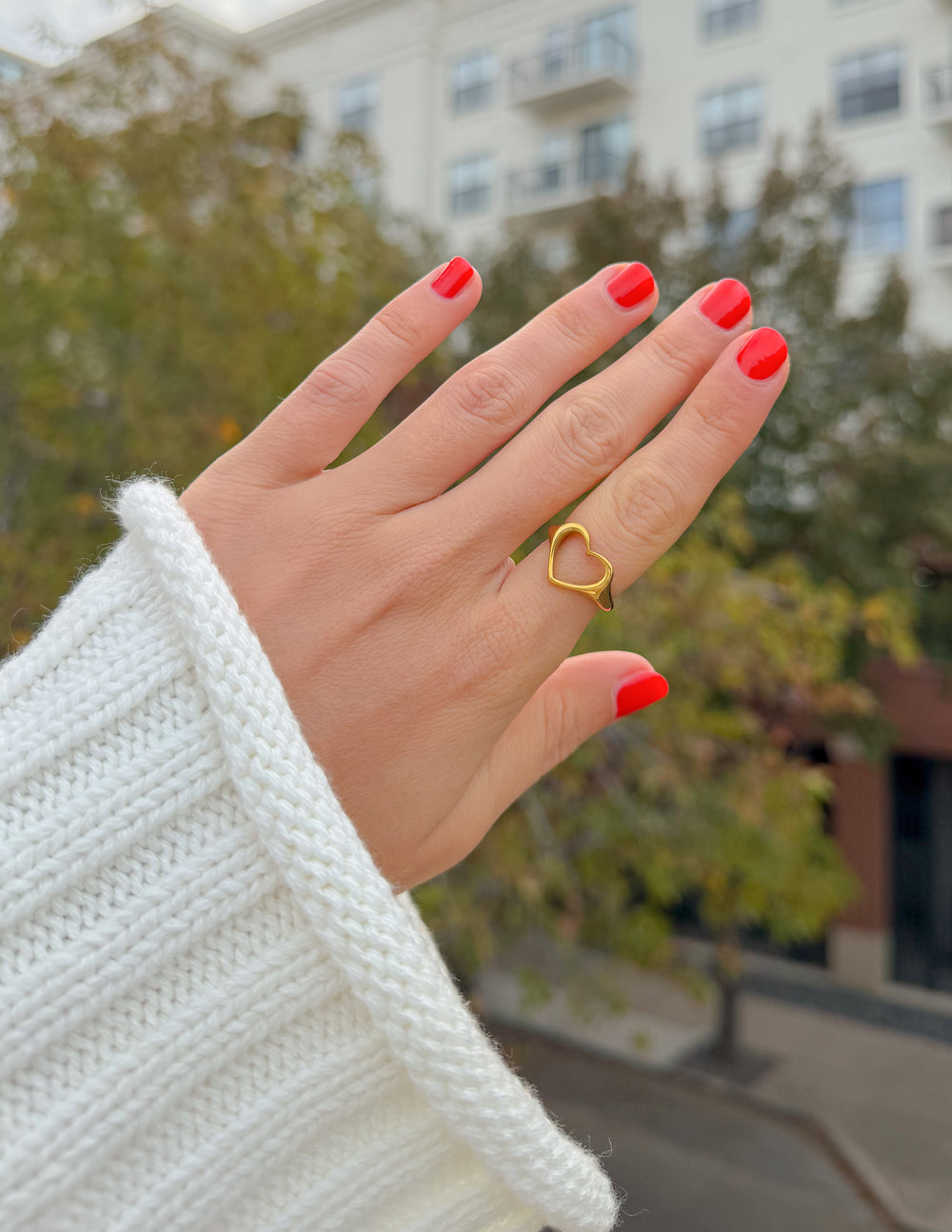 Gold-tone open heart ring on finger, heart-shaped cutout.