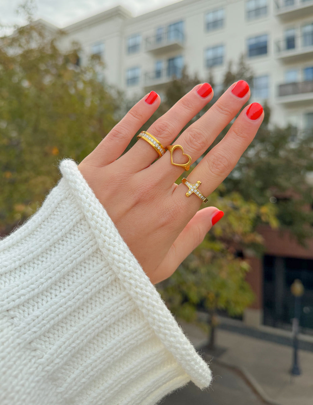 Gold-tone open heart ring stacked with a cross ring, heart-shaped cutout.