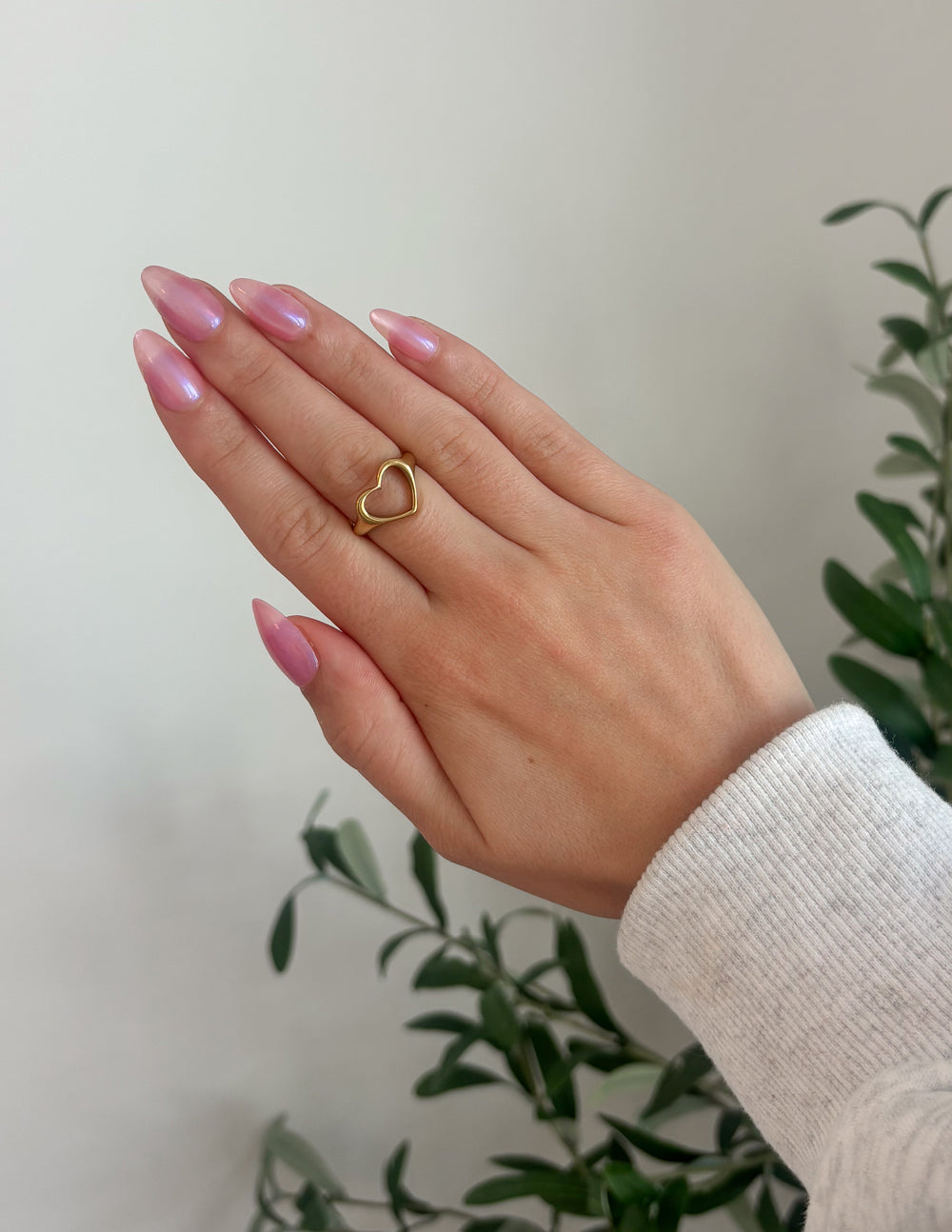 Gold-tone open heart ring on finger, heart-shaped cutout.