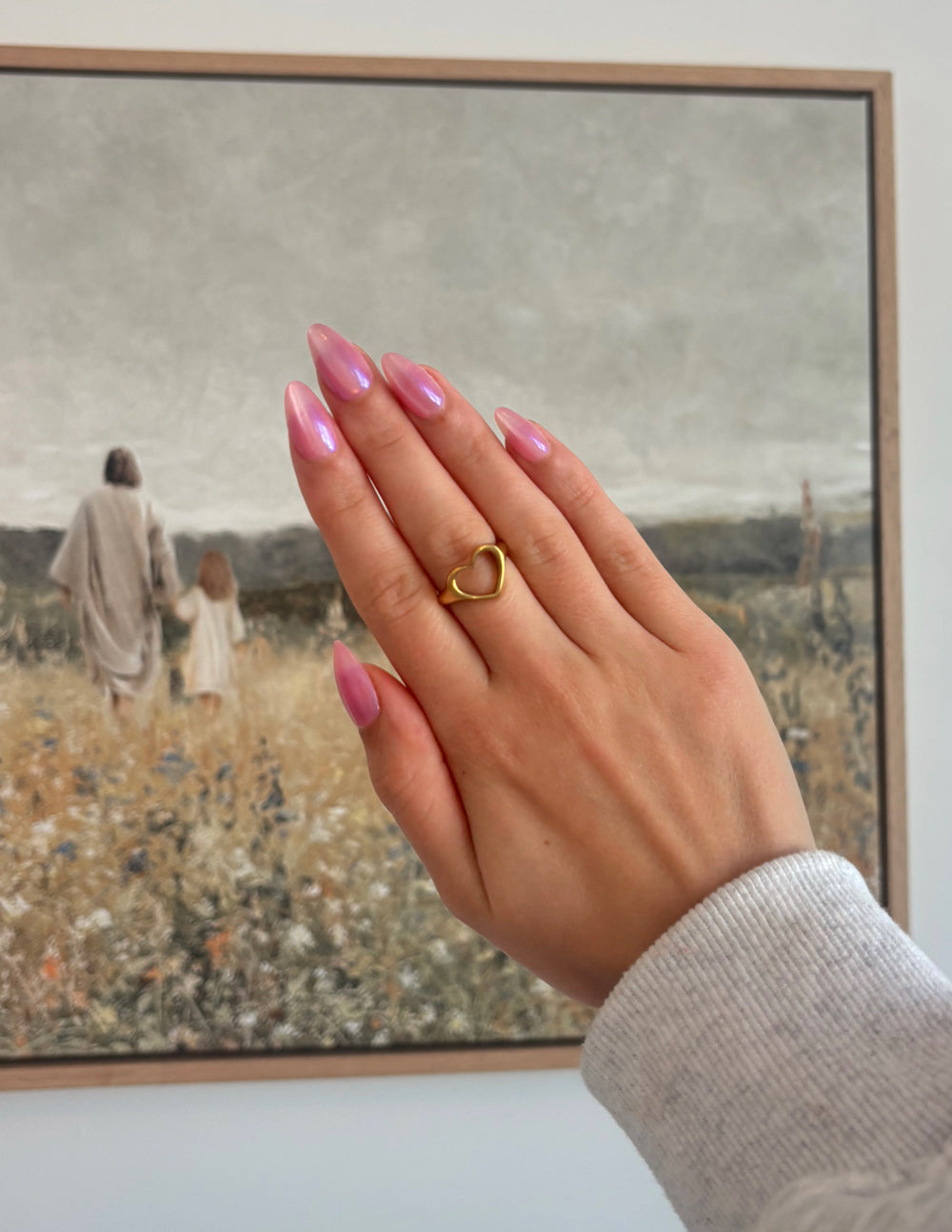 Gold-tone open heart ring on finger, heart-shaped open band.