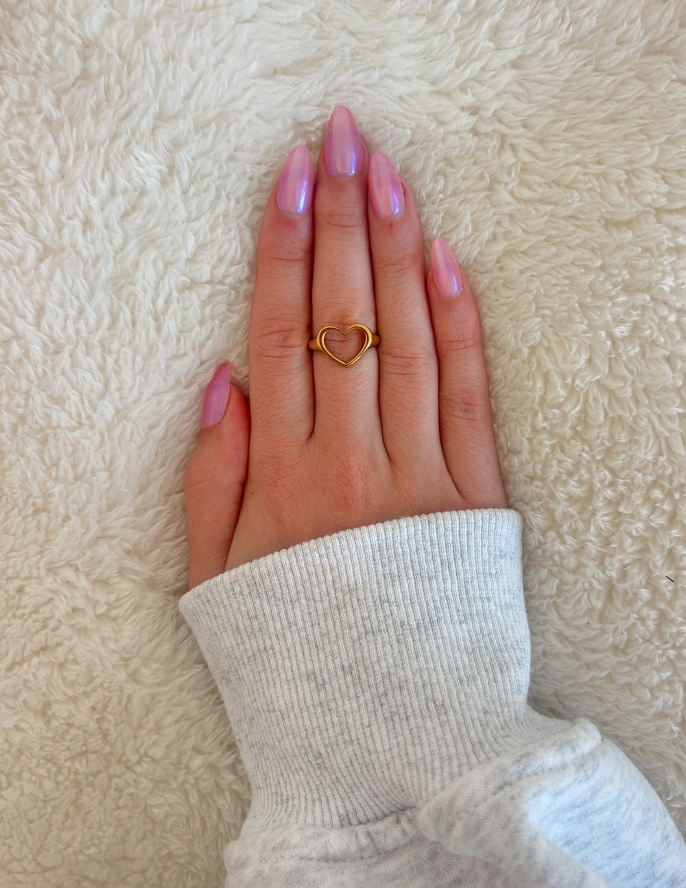 Gold-tone open heart ring on finger, heart-shaped cutout.