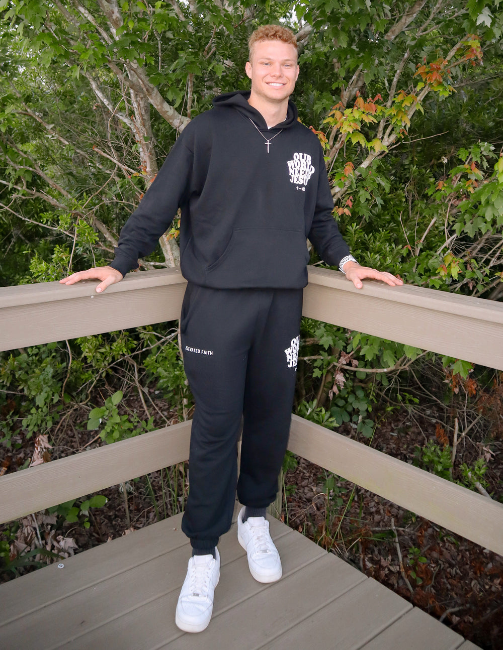 Black unisex sweatpants with white Our World Needs Jesus logo and cuffed hems
