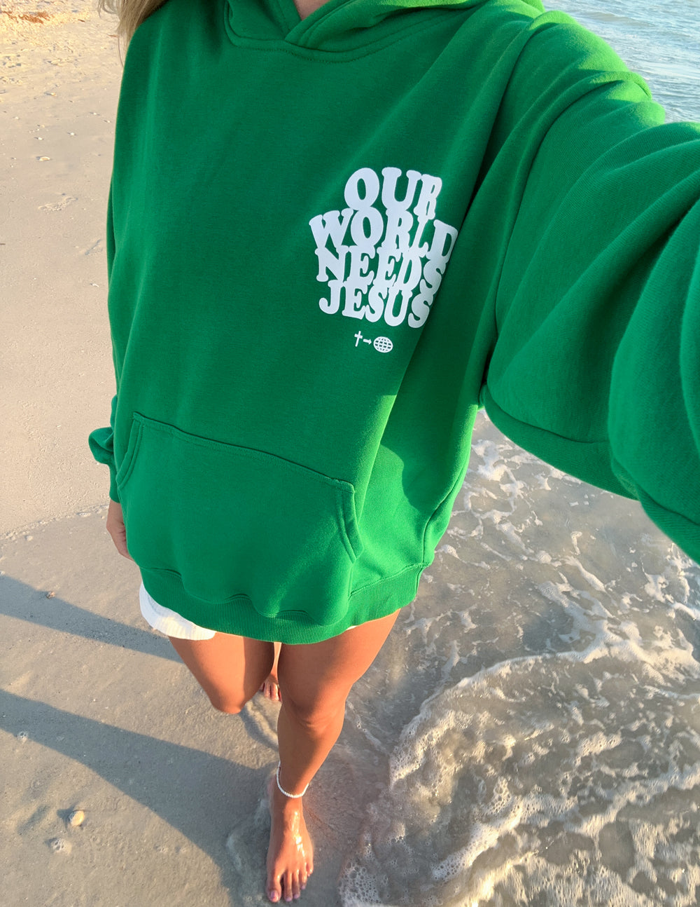 Close-up of green unisex hoodie showing white chest logo and pocket seam