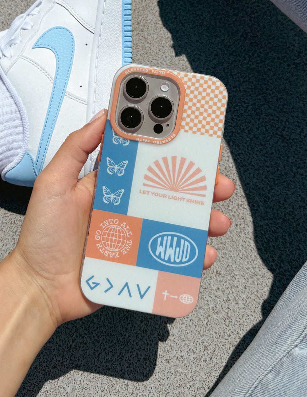 Patchwork phone case held in hand, butterfly and sunburst graphics, orange check, camera cutouts
