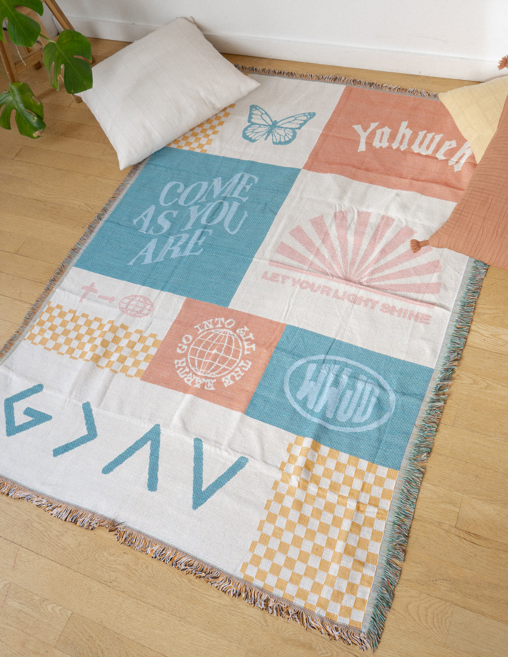 Patchwork throw blanket spread out with pastel teal, orange, and cream patchwork, fringe