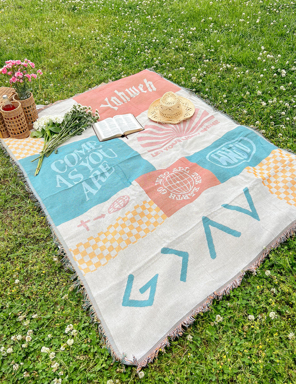 Patchwork throw blanket with pastel orange, teal, and cream blocks, fringed edges