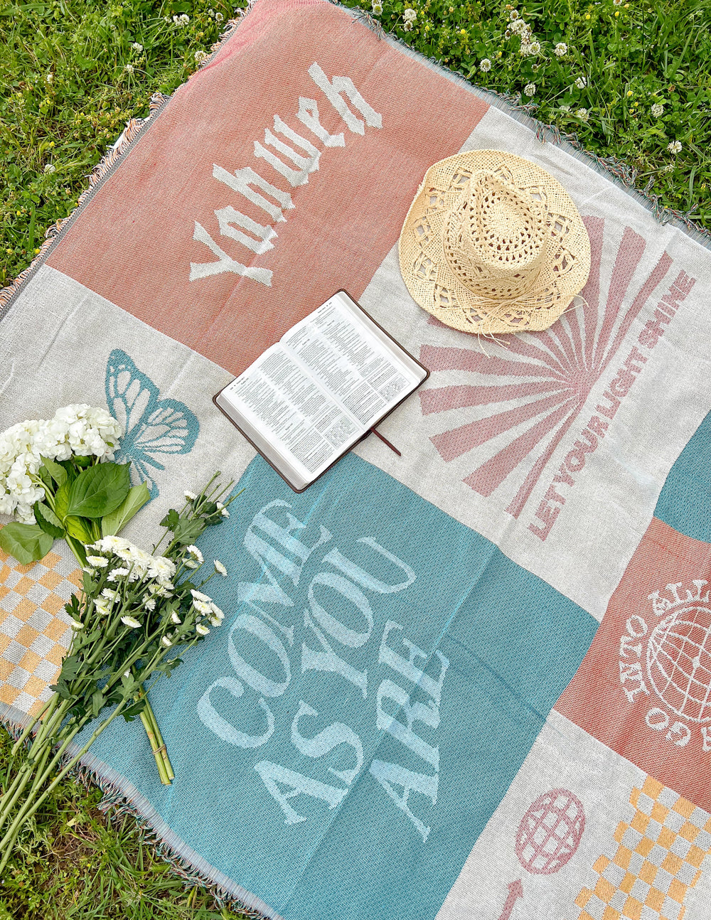 Patchwork throw blanket with pastel orange and teal panels, printed text, fringed border