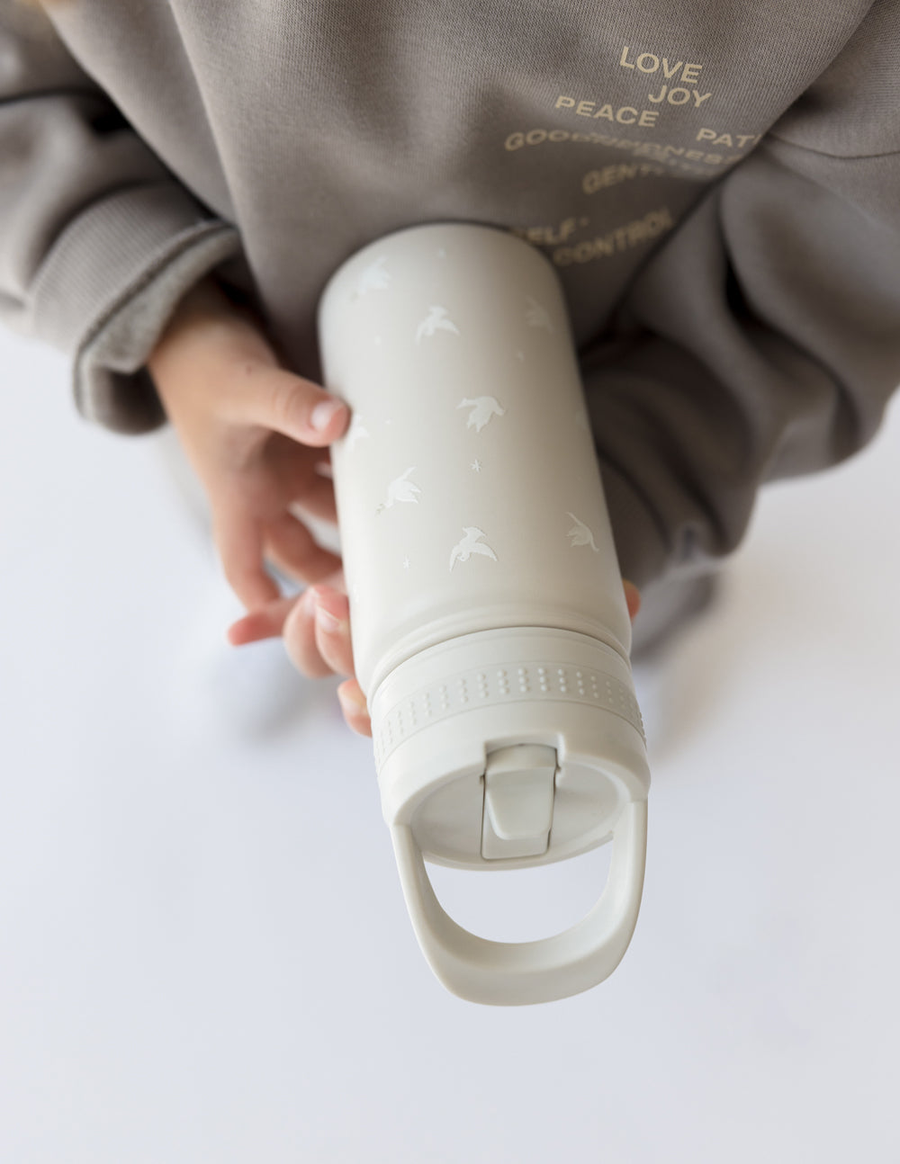Pale gray kids water bottle with straw spout, close-up of drinking nozzle