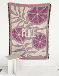 Throw blanket with purple floral pattern, 'Peace' print, and pink fringed edge