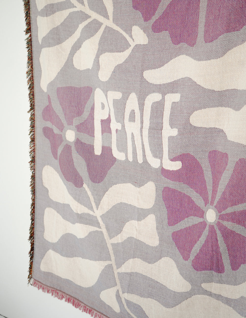Close-up throw blanket showing 'Peace' text on purple and cream floral pattern