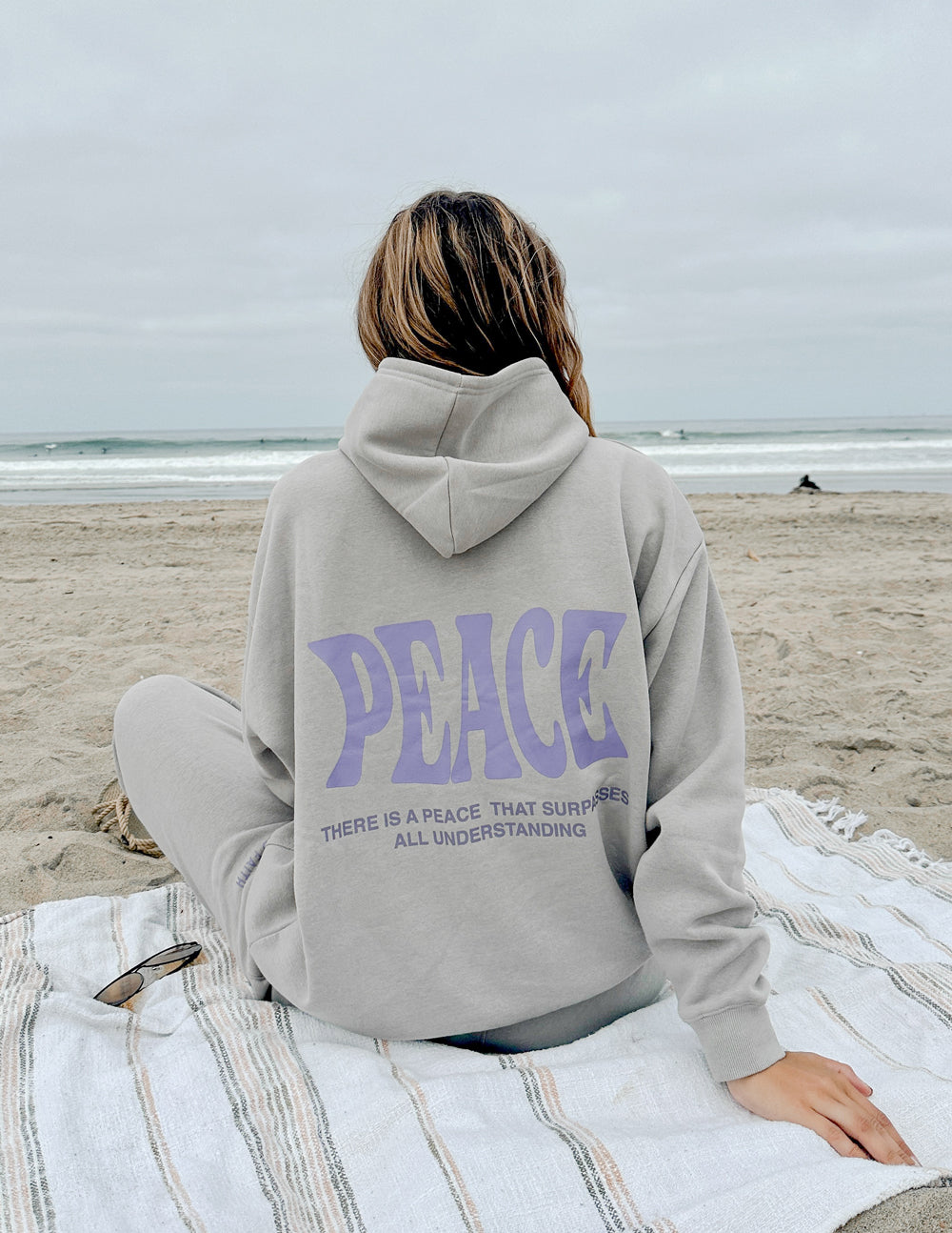 Light gray unisex hoodie with purple "PEACE" graphic on back, hood, and pouch pocket.