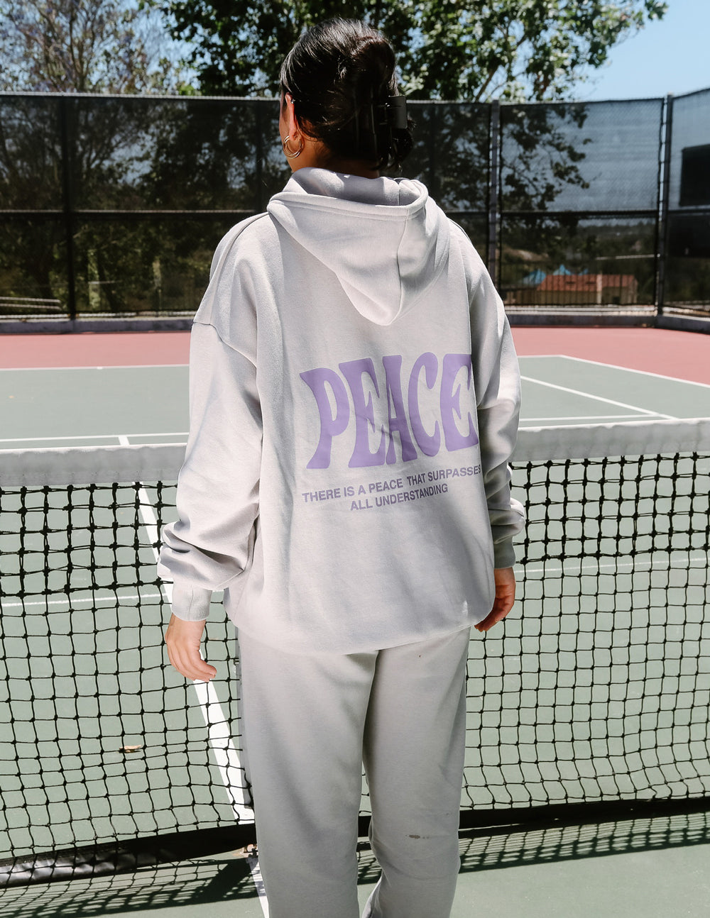 White unisex hoodie with purple "PEACE" graphic on back and hood