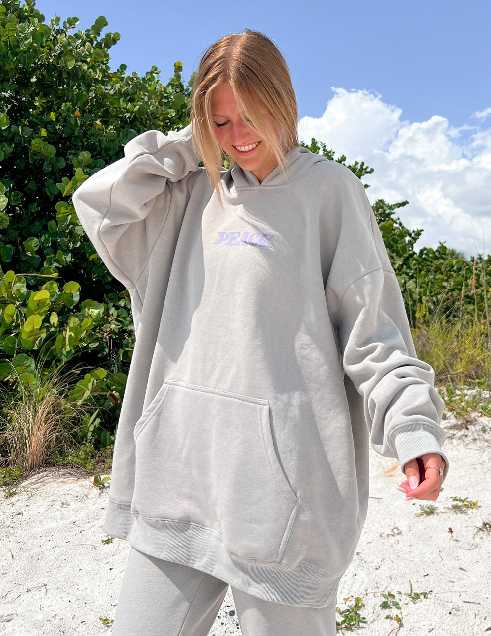 Light gray unisex hoodie with purple "PEACE" logo on chest, hood, and kangaroo pocket.