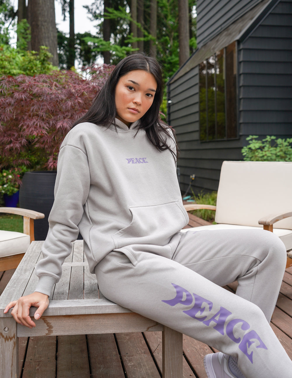 Unisex sweatpants, light gray with purple Peace logo print, seated pose