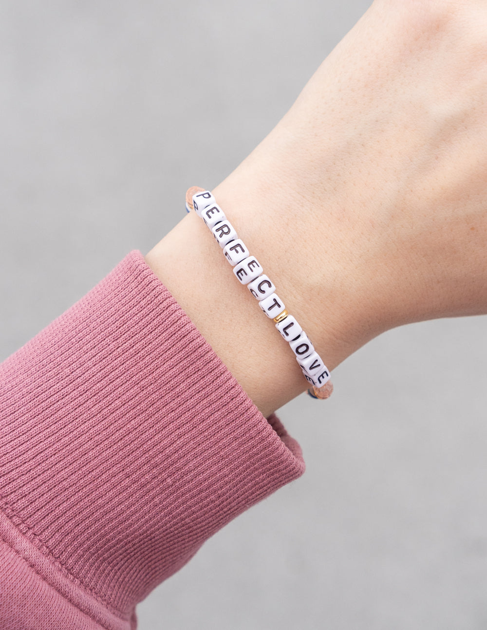 PerfectLove beaded bracelet on wrist with white letters and blue-pink beads